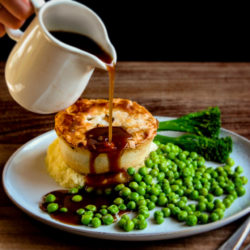 pieminister pie with pouring gravy and green veg